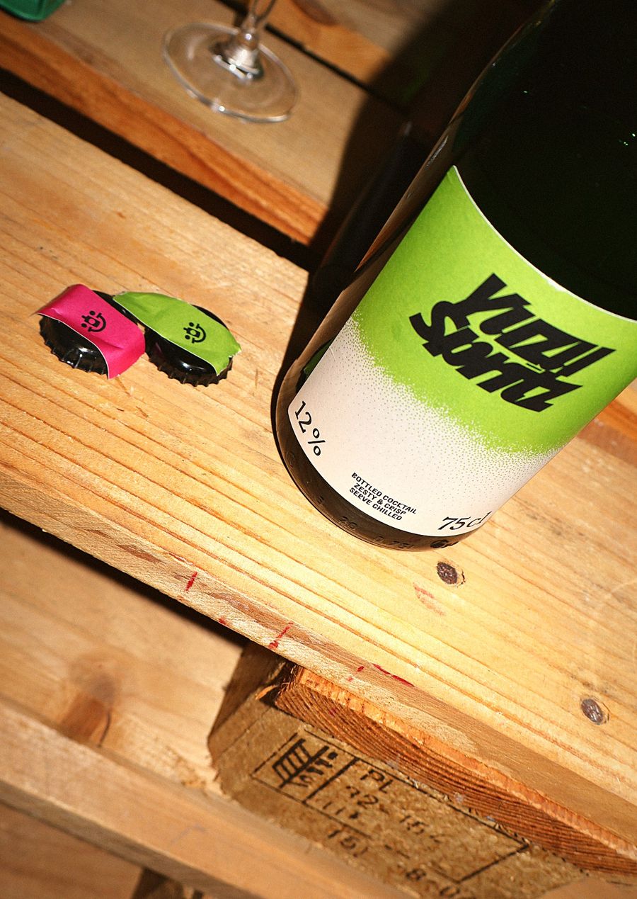 Flasche Yuzu Spritz mit grünem Etikett auf einer Holzpalette